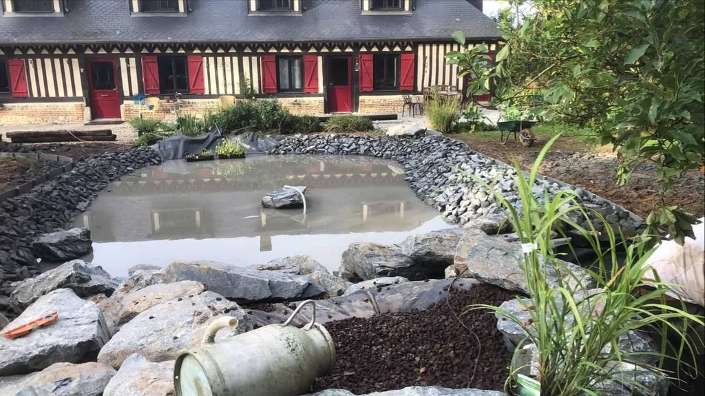 Aménagement en cours d'un bassin avec roches et décorations en Normandie