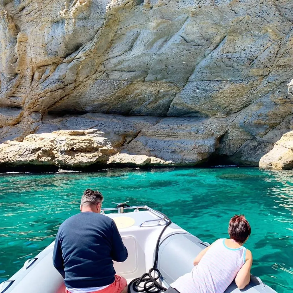 Groupe de passagers sur les bains de soleil d'un bateau de L'Eden Boat, taud de soleil déployé, Calanques en arrière-plan