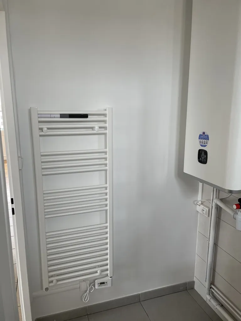 Salle de bain rénovée avec installation d’un chauffe-eau et d’un radiateur électrique pour améliorer le confort thermique