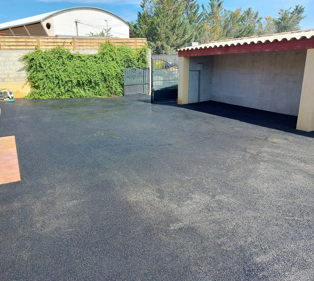 Application d'enrobé de bitume noir dans la cour d'une villa à Saint-Maximin la Sainte-Baume, dans le Var