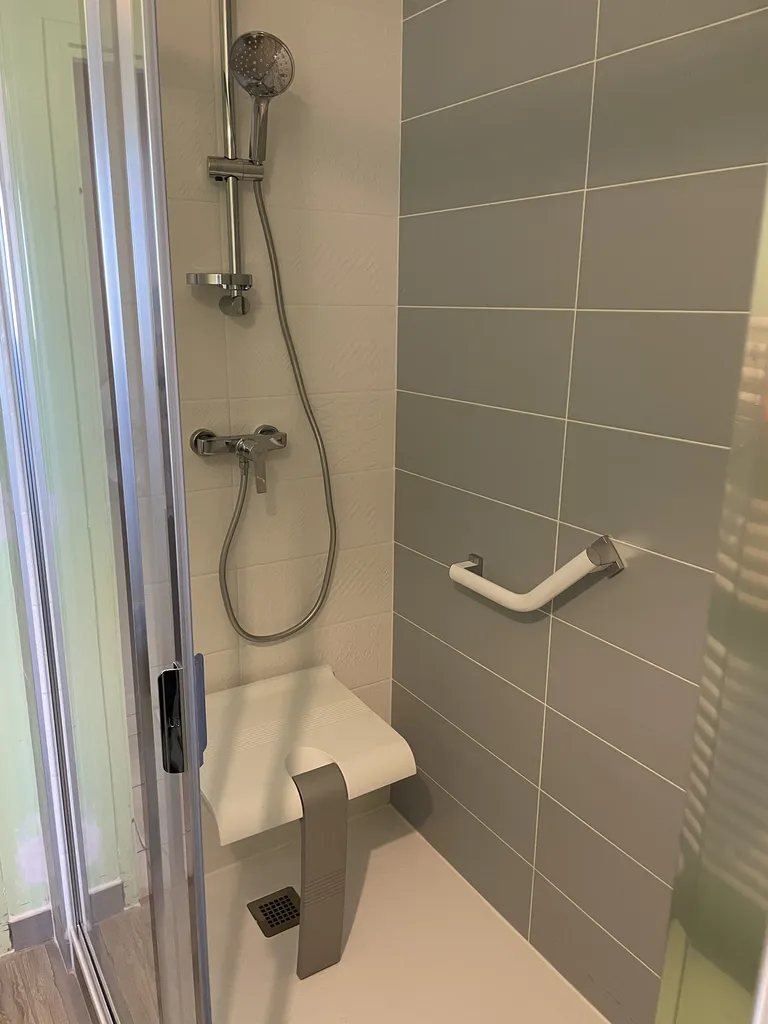 Douche sécurisée conforme aux normes PMR installée à Belleville-en-Beaujolais près de Villefranche-sur-Saône, avec receveur extra-plat, barres d’appui et équipements adaptés.